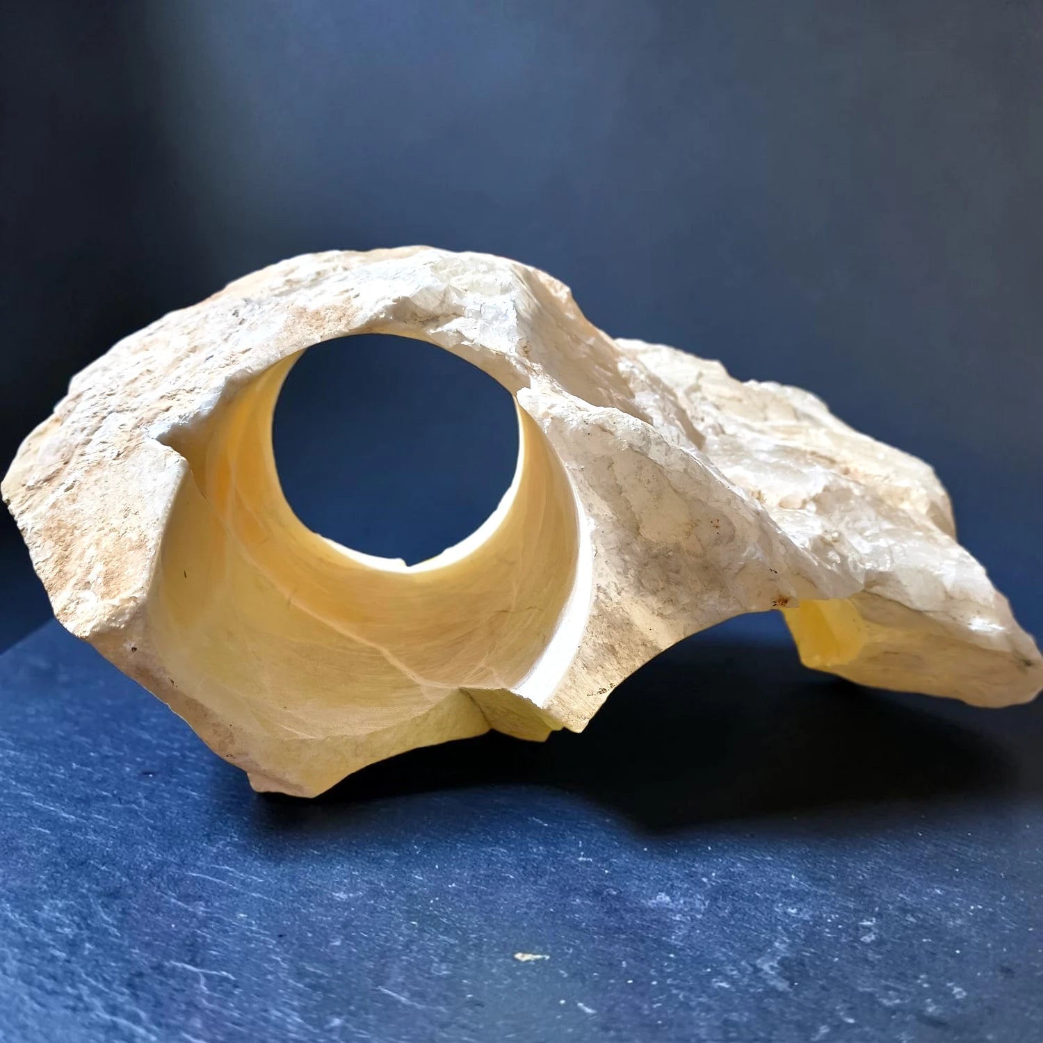 A large white natural onyx rock with a large swim-through holes for fish.